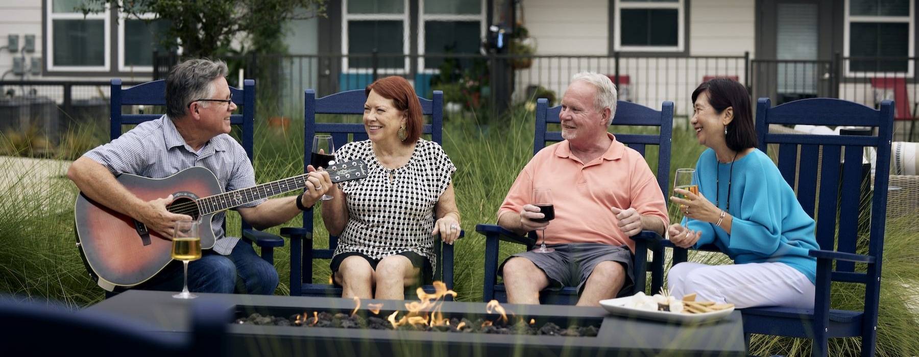 people sitting around fire and a man playing a guitar